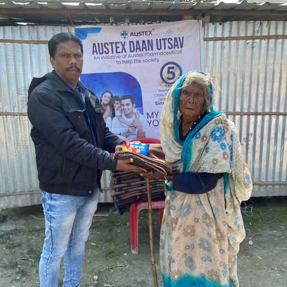 An Austex volunteer handing folded blankets to an elderly woman at the Daan Utsav drive